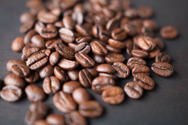 Overflow of freshly roasted coffee beans in front of a black background