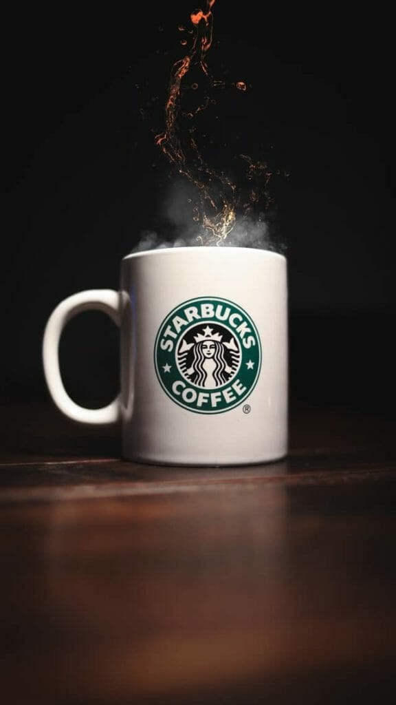  Best Hot Drinks at Starbucks: Steaming cup of coffee in a Starbucks branded cup