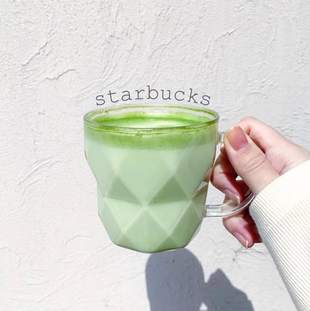 Woman holding a Starbucks Matcha Tea Latte in a geometric design glass mug