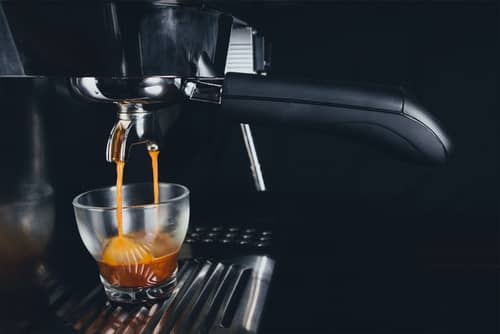 A shot of espresso pouring from an espresso coffee machine 