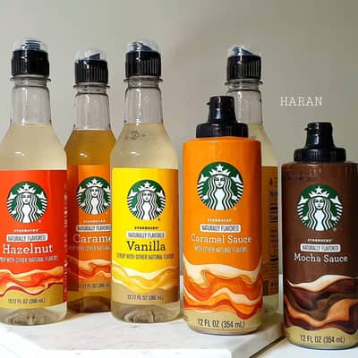 Starbucks caramel sauce and mocha sauce bottles among a selection of Starbucks syrup bottles
