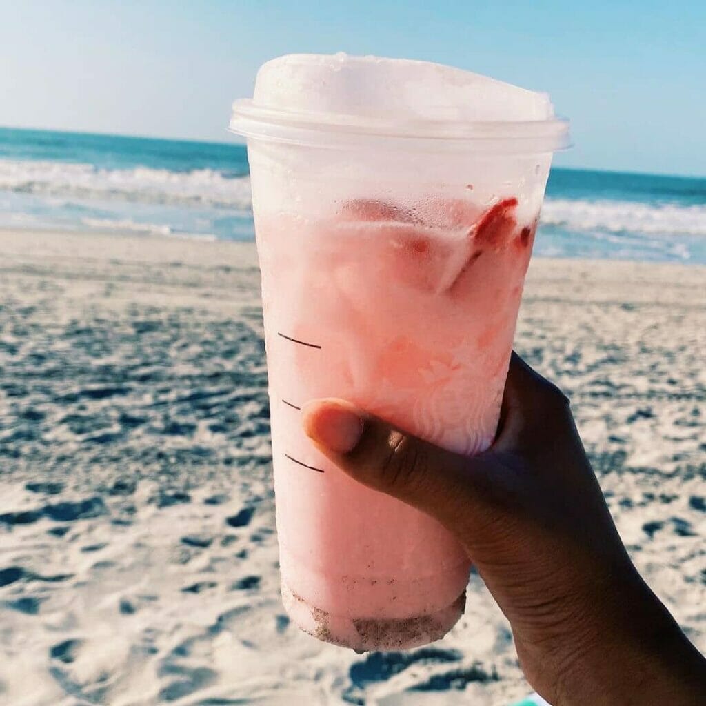 Shot of someone holding a Pink Drink at the beach