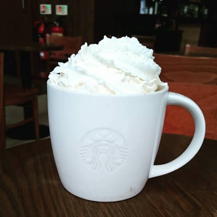 A white mug of Starbucks hot chocolate with cream