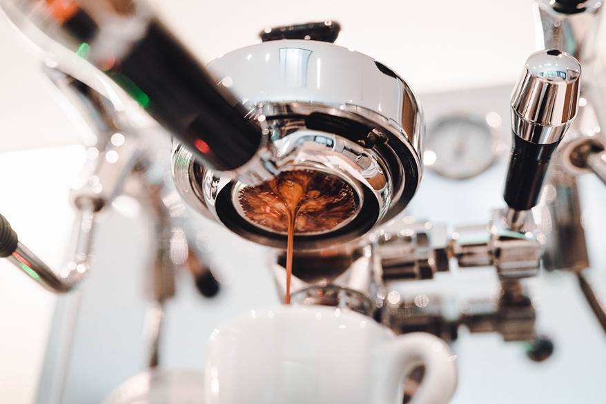 A white mug on espresso machine filling with coffee