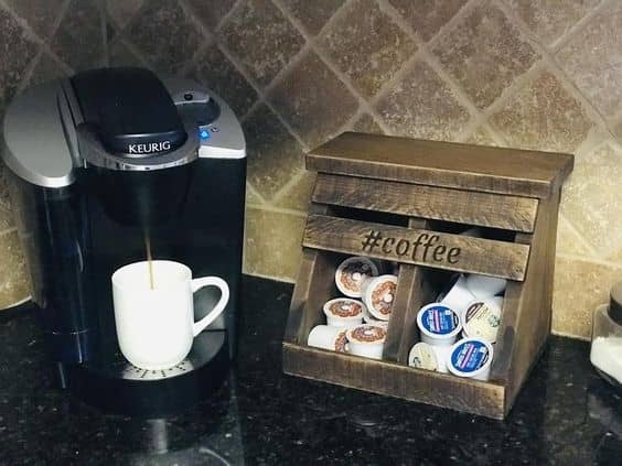 A keurig coffee maker next to a K cup holder with two sections