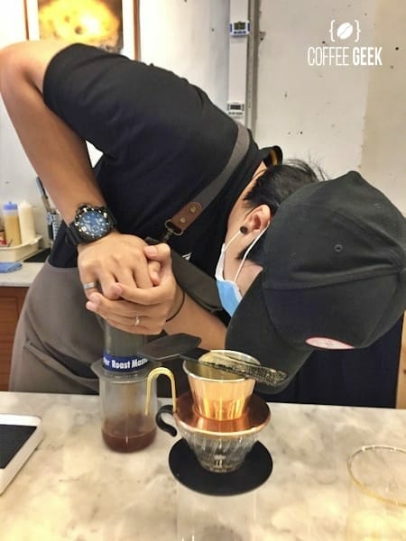A person making coffee using an aeropress