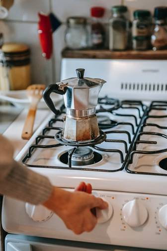 A Moka pot placed on a gas stove in the kitchen