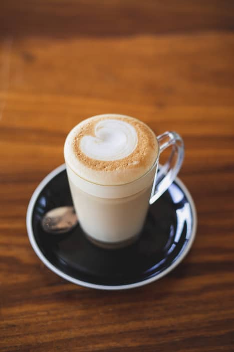 A Caffè Latte in a glass on a wooden surface