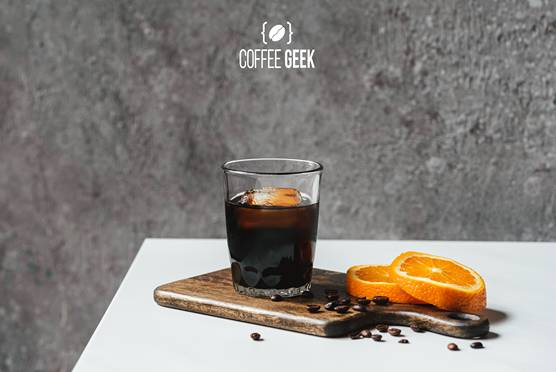 Cold brew coffee with ice in glass near orange slices 