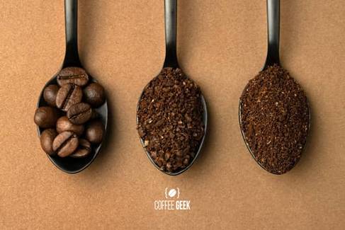 Darker-roasted coffee beans, medium-grind and medium-fine grind coffee in black spoons.