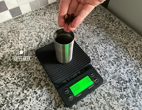 A black digital weighing scale measuring coffee beans