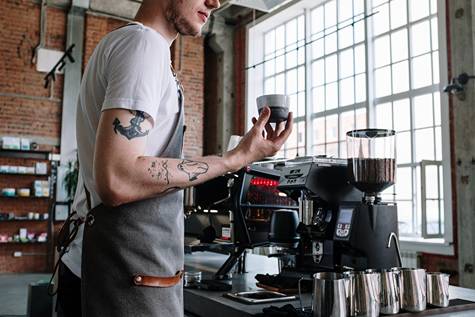 A barista standing in front of a coffee machine in a room