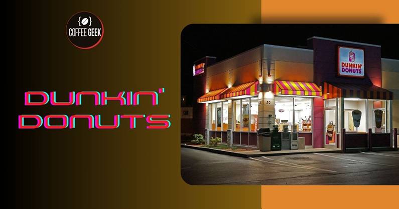 A dunkin' donuts store is lit up at night.
