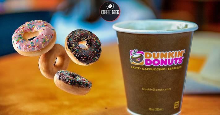 A dunkin donuts coffee cup with donuts on top.
