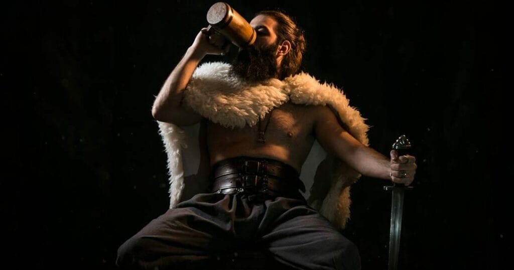 A man in a viking costume drinking a beer.