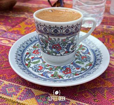A cup of turkish coffee on a colorful tablecloth.