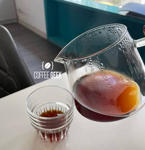 A person pouring coffee into a glass.