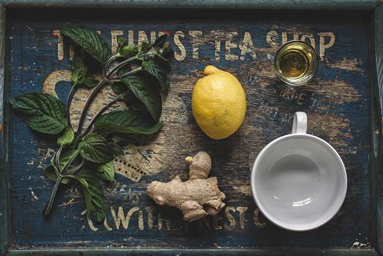 A tray with lemons, ginger, mint and a cup of tea.