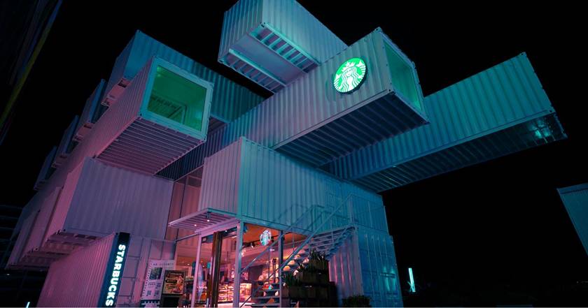 A starbucks store is lit up at night.