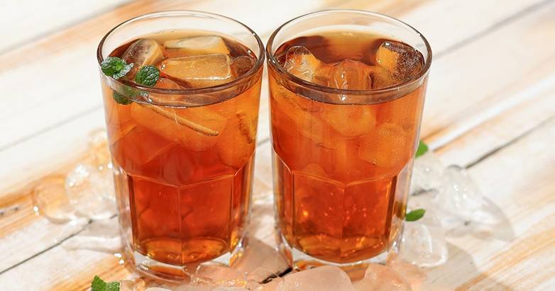 Two glasses of sweet iced tea on a wooden table.