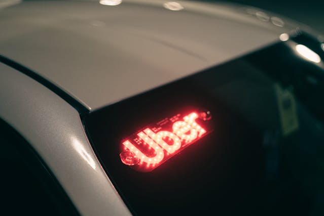 A car with a red illuminated Uber sign displayed in the rear window.